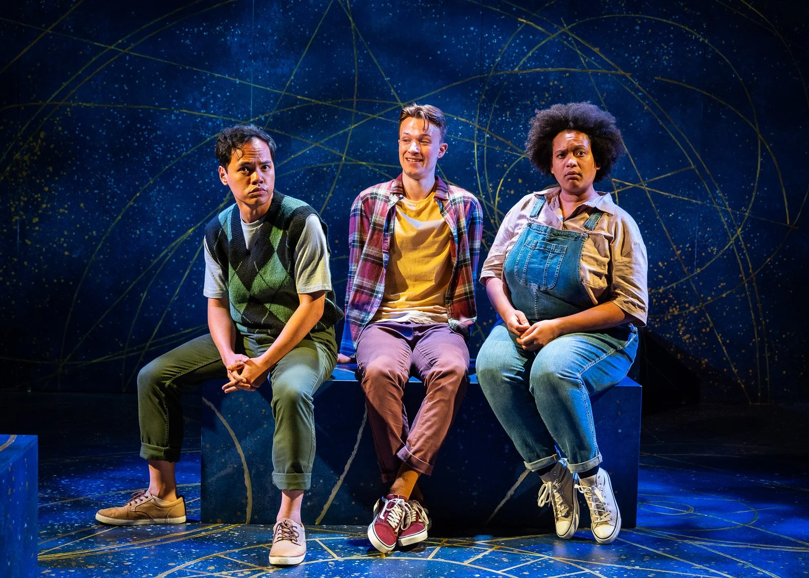 Three performers seated against a starlit set in Dumbledore Is So Gay